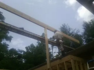 Carpenter setting a ridge beam over a new addition frame — Ice Dam Removal by Roofing Brothers in Galena Park