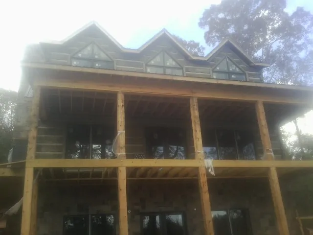 Dormers and porch framing on a large log home under construction — Roof Coating work by our crew in Galena Park