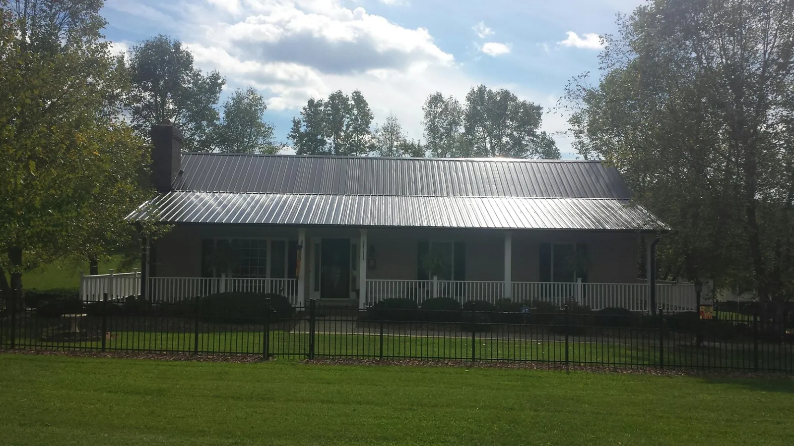 Gray metal roof on a brick ranch with a full width front porch — Gutter Guard Installation work by our crew in Galena Park