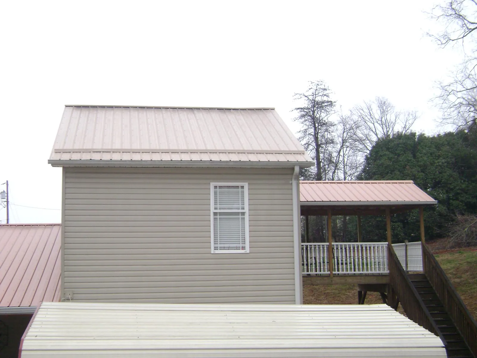 Tan metal roofs on a two story addition and attached porch, from a Roof Replacement job in Galena Park