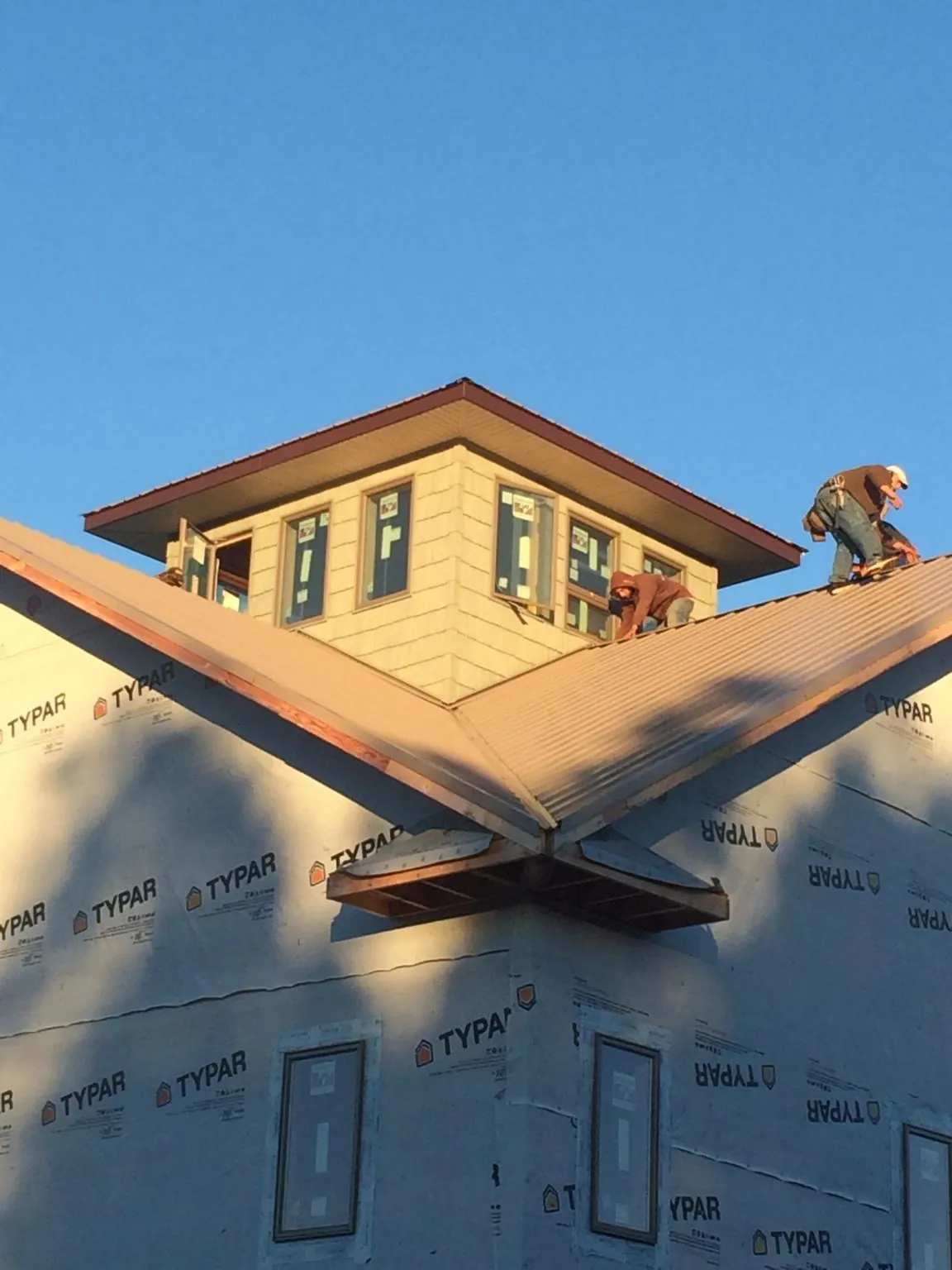 Roofers working around a rooftop cupola on a new metal roof at sunset — Roof Waterproofing in Galena Park by Roofing Brothers